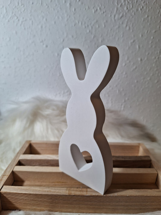 Ein schlichter aus keraflott gegossener weißer Hase mit einem mittigen Loch in Form eines Herzen.