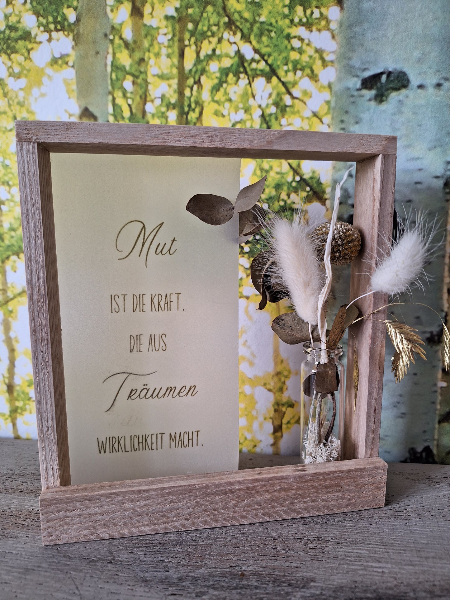 Holzrahmen mit Motivationsspruch auf Seidenpapier im Hintergrund, verziert mit einem Trockenblumenstrauß, elegantes Wanddekor