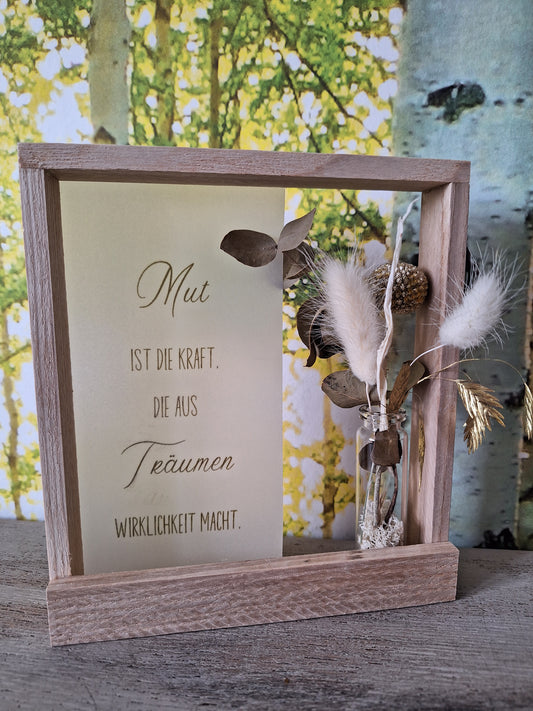 Holzrahmen mit Motivationsspruch auf Seidenpapier im Hintergrund, verziert mit einem Trockenblumenstrauß, elegantes Wanddekor