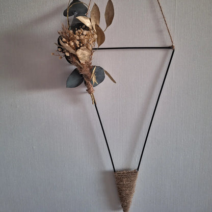 Moderne Wanddekoration aus dreieckigem Metallrahmen mit Trockenblumen und Jute – stilvolle Innendekoration