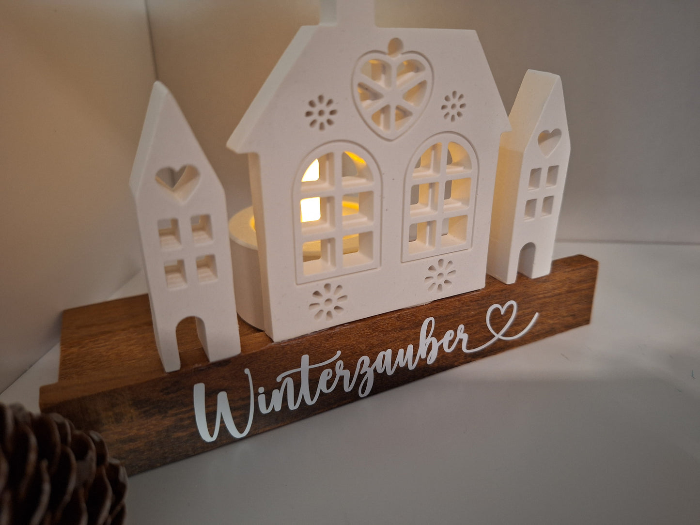 Dekoaufsteller mit Häusern welche indirekt beleuchtet werden können durch Teelichthalter dahinter. Steht auf Holzsockel. 
