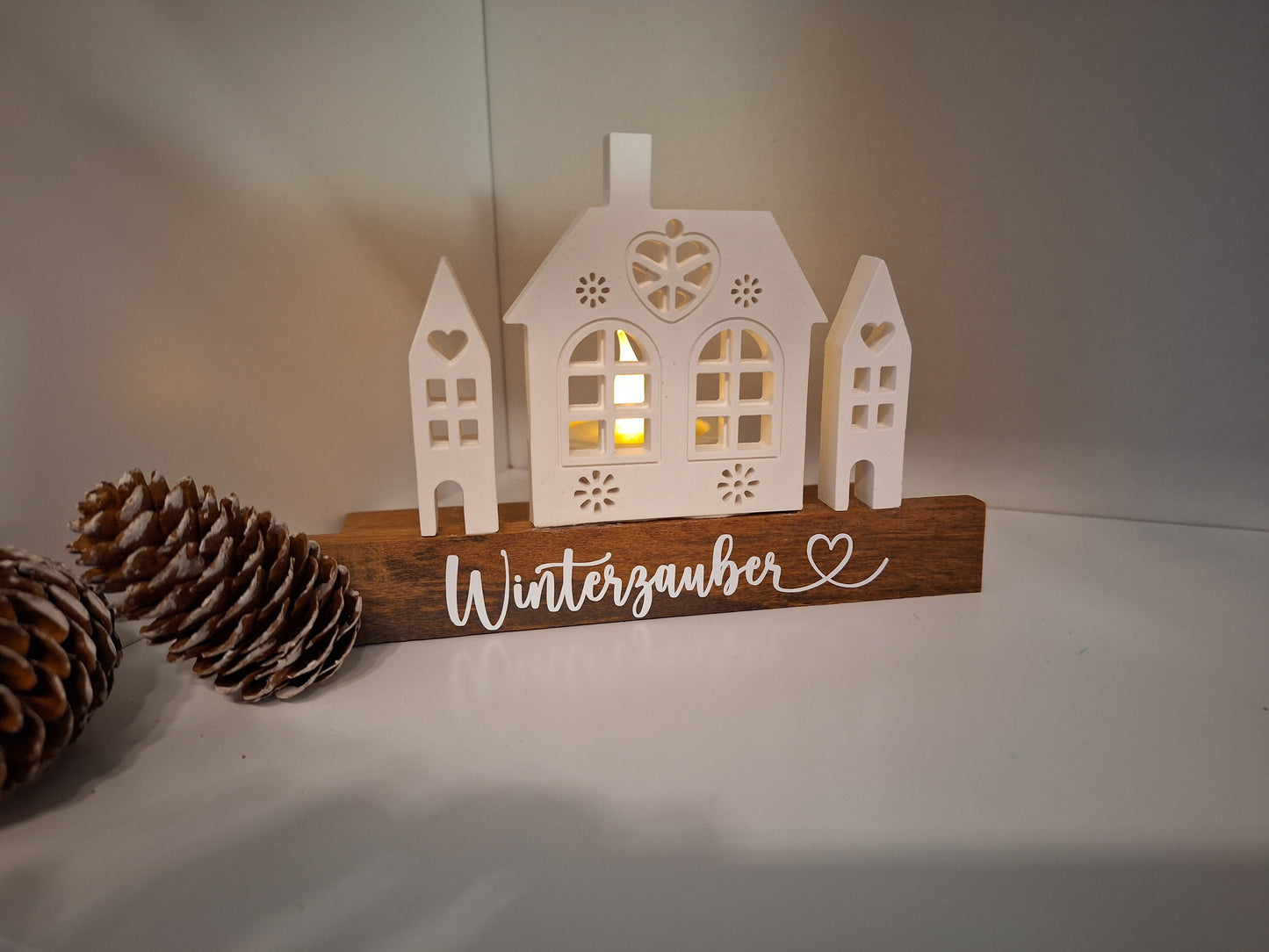 Dekoaufsteller mit Häusern welche indirekt beleuchtet werden können durch Teelichthalter dahinter. Steht auf Holzsockel. 